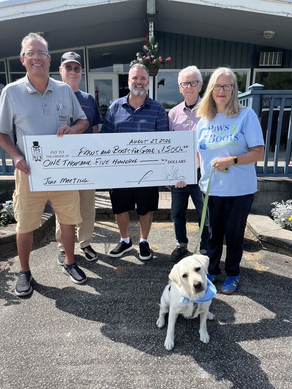 Group presenting a donation cheque with a yellow Labrador in front