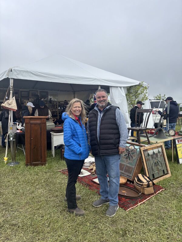 Fred Drodge and a woman at an outdoor tent with antique displays
