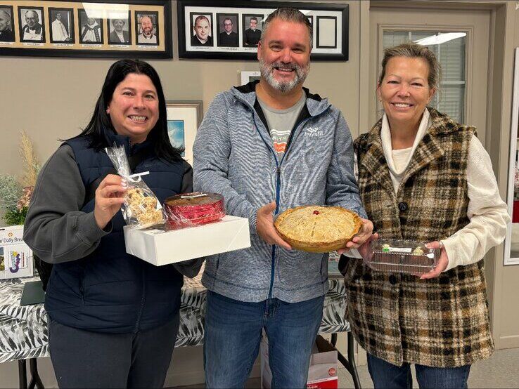 Fred Drodge holding a pie with two volunteers